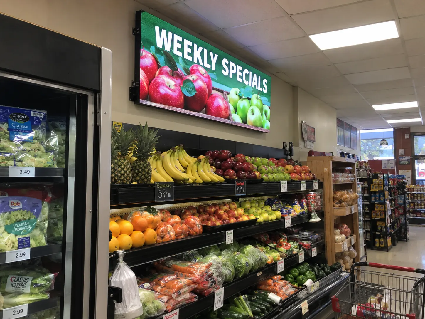 Indoor LED promotional display above produce in a grocery store